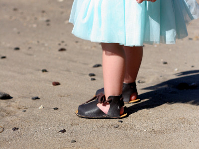 Kid wearing open toed sandals on the beach, perfect for allowing room for feet to grow!