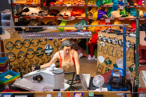 Person using press machine to cut out pieces of leather used to handcraft customized shoes