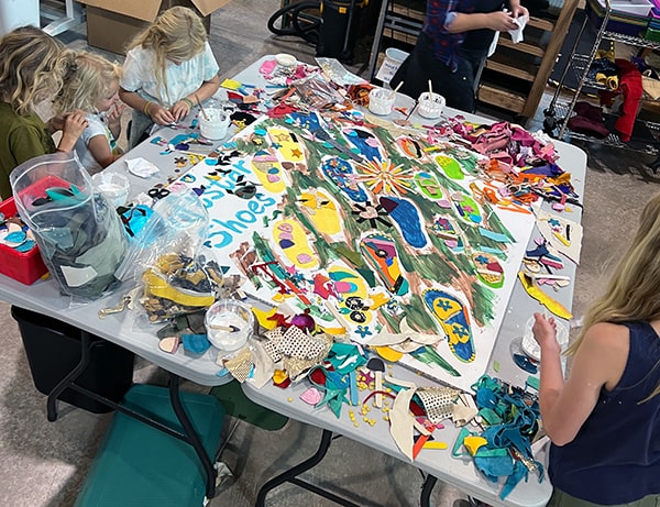 Kids gluing leather scraps to the mosaic
